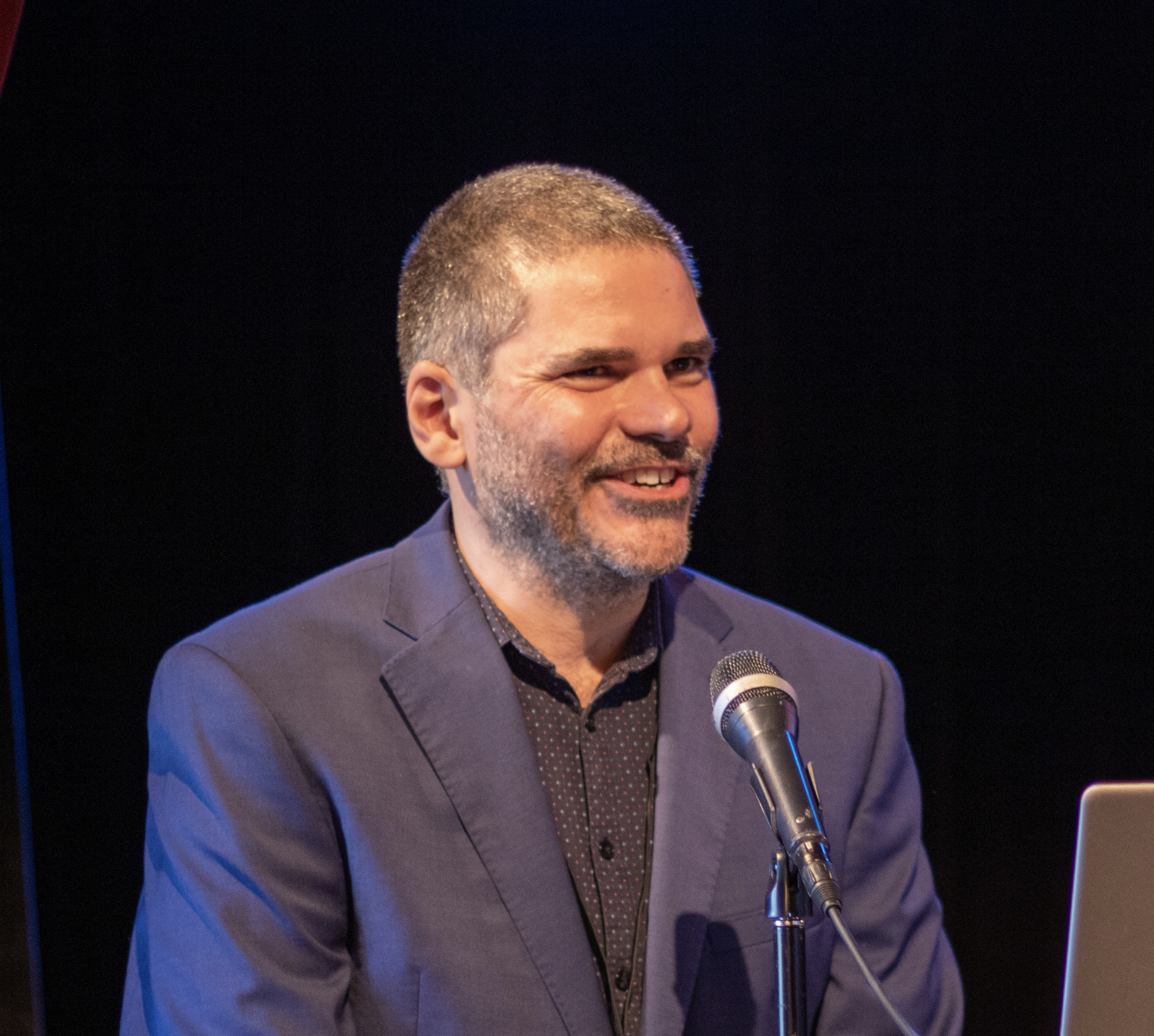 a profile picture of quinten sheriff sitting down, wearing a blue jacket and smiling.